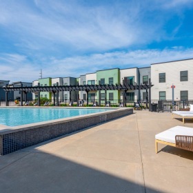 a pool with a lounge chair and a deck with chairs by it